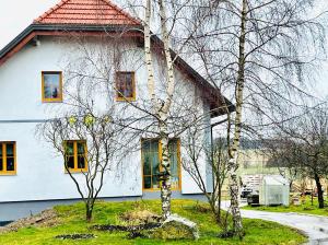 a white house with yellow windows and trees at Privatzimmer Fam. Führer in Ottenschlag