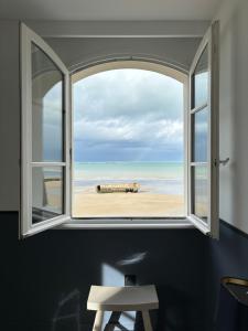an open window with a view of the beach at Hôtel De La Marine in Arromanches-les-Bains