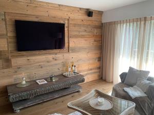 een woonkamer met een televisie aan een houten muur bij Appartement à deux pas du centre de Crans-Montana in Crans-Montana