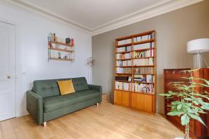 a living room with a green couch and a book shelf at Résidor - Haussmanian flat in the heart of Paris in Paris