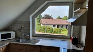 a window in a kitchen with a sink and a house at Klimatisierte Wohnung Kastanie mit Balkon in Löhne
