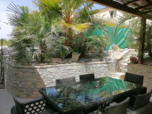 eine Terrasse mit einem Tisch, Stühlen und Palmen in der Unterkunft maison de rêve dans un écrin de verdure au calme in Eccica-Suarella