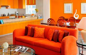 a living room with an orange couch and a kitchen at Marriott Executive Apartments Dubai Creek in Dubai