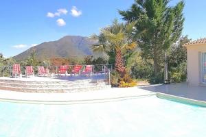 einen Pool mit Stühlen, Palmen und einem Berg in der Unterkunft maison de rêve dans un écrin de verdure au calme in Eccica-Suarella