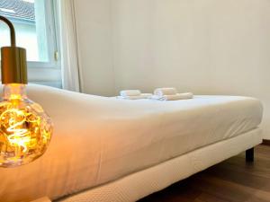a white bed with a lamp next to a window at Floréa Reims avec du charme proche gare et centre in Reims