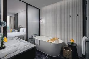 Crowne Plaza Ezhou, an IHG Hotel في Ezhou: حمام مع حوض استحمام وغرفة نوم