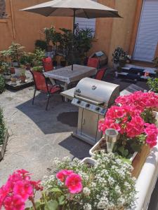 a patio with a grill and some pink flowers at Baross-hat 5 in Szolnok