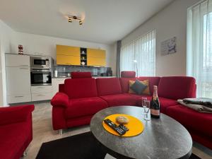 ein Wohnzimmer mit einem roten Sofa und einem Tisch in der Unterkunft Strandloft-Frieshörn Nordsee Park Dangast in Dangast