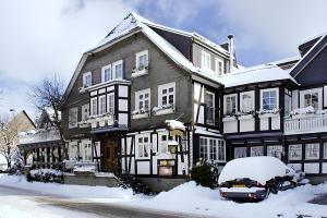 a snow covered house with a car parked in front of it at Landhotel Albers in Schmallenberg