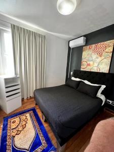 a bedroom with a black bed and a rug at Hotel Boutique Tremo Bellavista Suite in Santiago