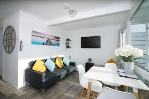 a living room with a black couch and yellow pillows at Sea Lavender Holiday Chalet, close to sandy beach in Heacham