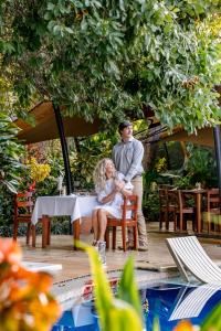 a man standing next to a woman sitting at a table at Shongwe Oasis in Victoria Falls