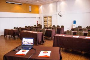 ein Zimmer mit Tischen und Stühlen und einem Laptop auf einem Tisch in der Unterkunft Hotel Nippon y Centro de Eventos in Santiago