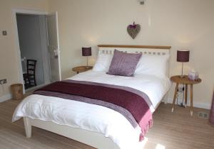 a bedroom with a white bed with a purple blanket at Dinmore in Richmond