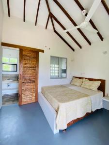 a bedroom with a large bed and a bathroom at Cabaña cerca al Mar con Pisicina y AC en Tolú in Tolú