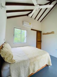 a bedroom with a white bed with a ceiling fan at Cabaña cerca al Mar con Pisicina y AC en Tolú in Tolú