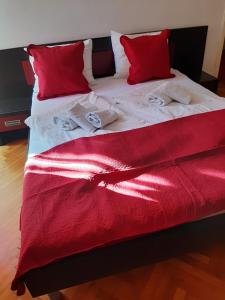 - un lit avec des draps et des oreillers rouges et blancs dans l'établissement Apartments Vila Miranda 2, à Barbat na Rabu