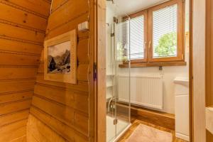 a bathroom with wooden walls and a glass shower stall at Domek Siuster w regionalnym stylu z widokiem na góry - doskonała lokalizacja, niedaleko Term Bukovina in Bukowina Tatrzańska