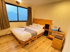 Schlafzimmer mit einem Bett, einem Schreibtisch und einem Fenster in der Unterkunft Mountain View cafe in Pokhara