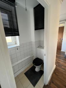 a bathroom with a toilet with a black seat at Bethnal green home in London