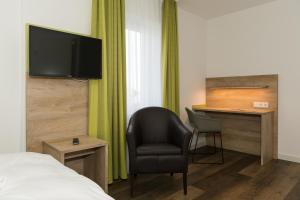 a hotel room with a bed and a chair and a desk at Roca Restaurant und Hotel in Bommersheim