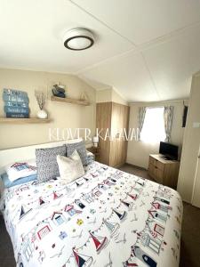 1 dormitorio con 1 cama grande con colcha y libros. en Seton Sands Holiday Park Klover Karavans, en Port Seton