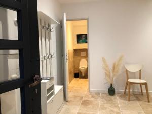 a hallway with a bathroom with a toilet and a chair at La Figuière in Manosque