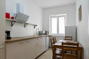 cocina con armarios blancos, mesa y sillas en Sunny Side - Apartment by Comfort Housing, en Falkensee