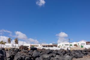 a pile of rocks on the beach with buildings in the background at Casa Ana y el Mar - Para Enamorados del Mar - en Lanzarote in Teguise