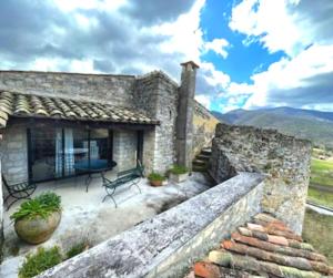 Un edificio de piedra con un banco en un patio. en Commanderie Vue Panoramique 2 chambres, en Le Poët-Laval