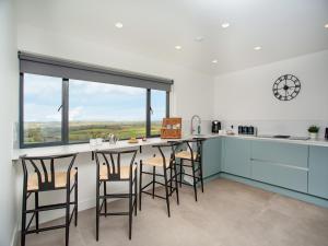 a kitchen with a bar with chairs and a clock on the wall at Deer View in Ottery Saint Mary