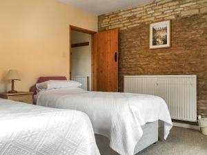 um quarto com 2 camas e uma parede de tijolos em The Mill House em Lea