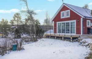 una casa roja con terraza en la nieve en Lovely Home In kersberga With Wifi, en Åkersberga
