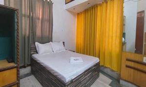 een kleine slaapkamer met een bed met gele gordijnen bij FabExpress Avenue villa in kolkata