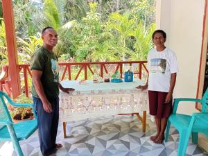 a man and a woman standing in a room with a table at Delima Cottage New Room in Langgur