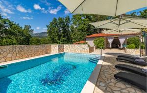 a swimming pool with chairs and an umbrella at Lovely Apartment In Jadranovo With Wifi in Jadranovo