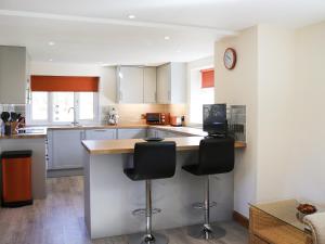 a kitchen with a counter and two bar stools at Bwthyn Glanllyn in Llanuwchllyn