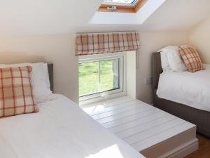 a bedroom with two beds and a window at Bwthyn Glanllyn in Llanuwchllyn
