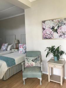 una camera con un letto, una sedia e un quadro di Cherry Berry Lodge a George