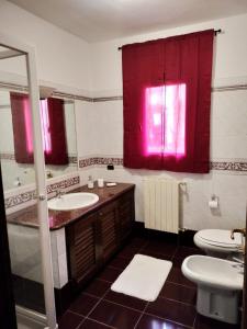 La salle de bains est pourvue d'un lavabo, de toilettes et de rideaux rouges. dans l'établissement Bandi House, à San Teodoro