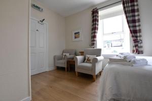 a bedroom with a bed and two chairs and a window at Argyll House Burnside in Salen