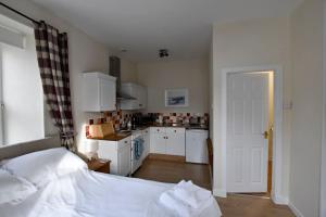 1 dormitorio con 1 cama y cocina con armarios blancos en Argyll House Burnside, en Salen