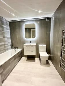 Seafront Apartment في نيوكاسل: حمام مع مرحاض ومغسلة وحوض استحمام