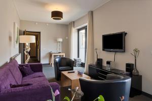 salon z fioletową kanapą i telewizorem w obiekcie Hunzego Hotel w mieście Uithuizermeeden
