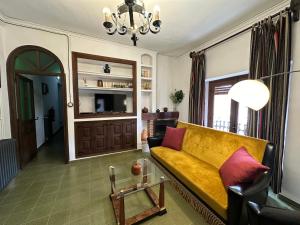 a living room with a yellow couch and a table at Casa Rural del Juez in Alcalá del Júcar