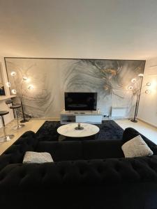 sala de estar con sofá negro y TV en BY NEPTUNE - Appartement Disney Paris - 1 min RER en Chessy
