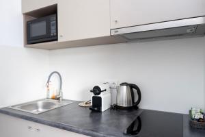 um balcão de cozinha com um lavatório e um micro-ondas em Comfort Housing Apartments em Falkensee