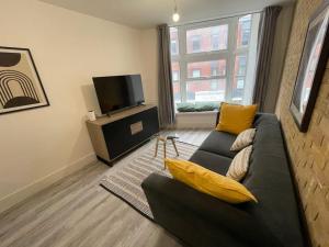a living room with a black couch and a tv at Stunning 1 bed central flat in Woking