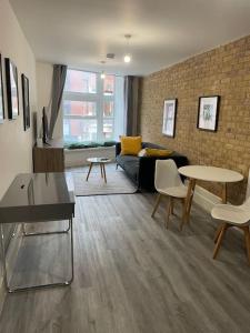 a living room with a couch and tables and a brick wall at Stunning 1 bed central flat in Woking