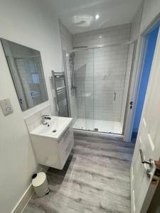 ウォーキングにあるStunning 1 bed central flatの白いバスルーム(シンク、シャワー付)